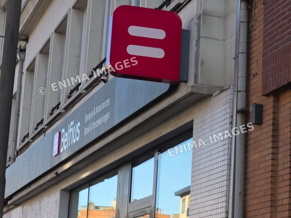 Logo rouge Belfius et enseigne bilingue Banque et Assurances sur la façade vitrée d’une agence.